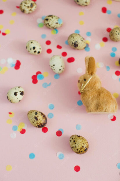 Quail eggs with a plush bunny and colorful confetti on a pink surface