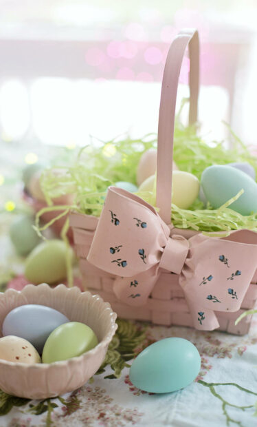 pastel colored eggs with spring decoration in a basket and bowl