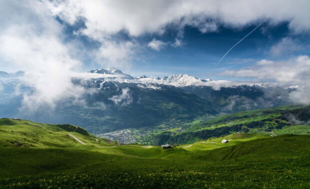Rolling green hills and snowy mountains create a peaceful spring landscape