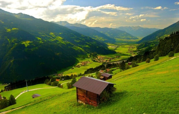 Wooden cabin surrounded by green hills and mountains in spring mountain scenery