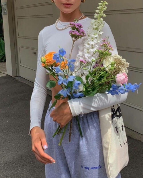 A woman holding a spring bouquet of colorful flowers in casual clothes