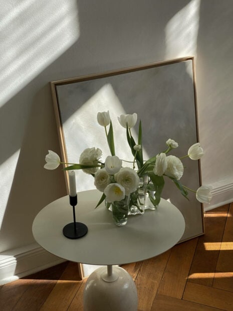 White tulips arrangement in a glass vase on a modern round table in soft natural light