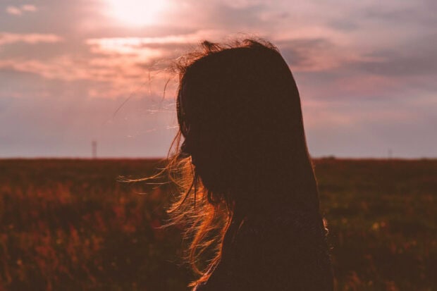 silhouette of a woman with hair blowing in summer breeze