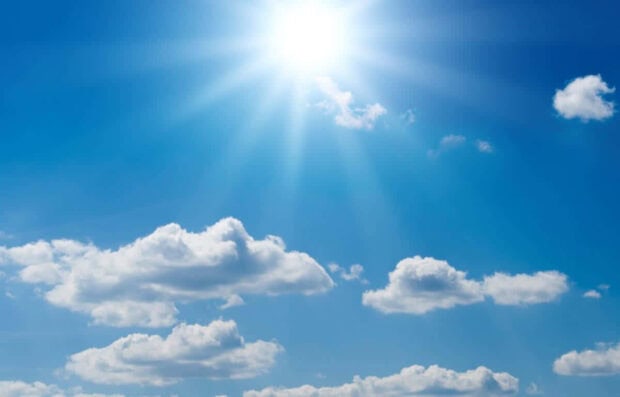 Bright blue sky with summer clouds and shining sun rays