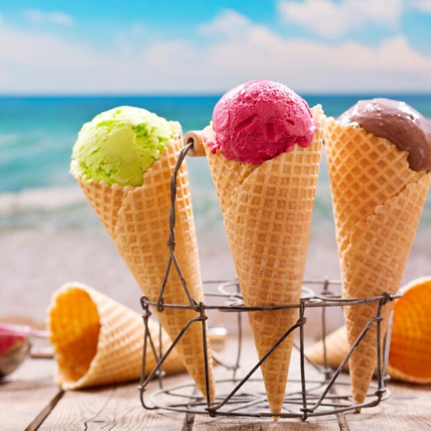 Colorful summer ice cream cones on a wooden table by the sea