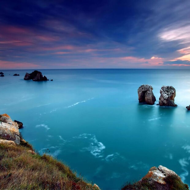 Summer sea and rocky coastline with calm water during summer twilight
