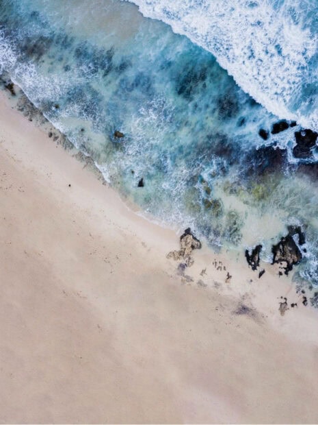 Aerial view of summer beach with clear water and sandy shore