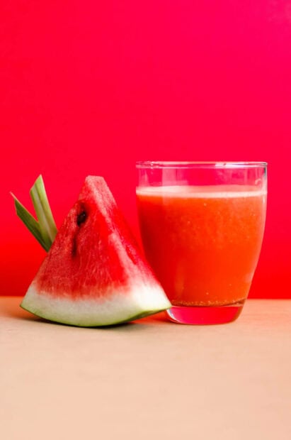 A fresh watermelon slice and juice on a table with summer vibrant colors