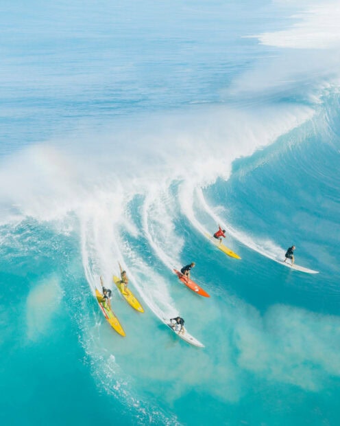 Surfers riding waves in turquoise ocean during summer