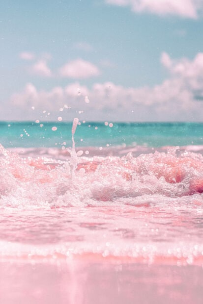 Pink ocean waves splash under a clear blue sky in summer sea scene