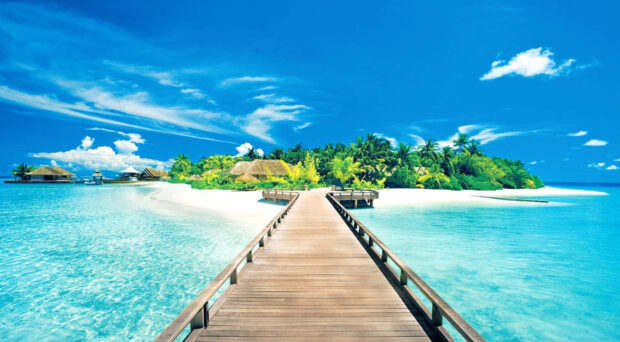 Tropical island with wooden dock and crystal clear water under blue sky in summertime