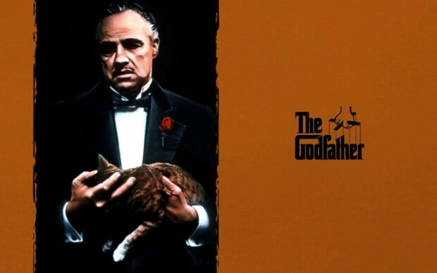 Vito Corleone, dressed in a tuxedo, cradles a tabby cat against a warm orange background, presented in a crisp 1080p format