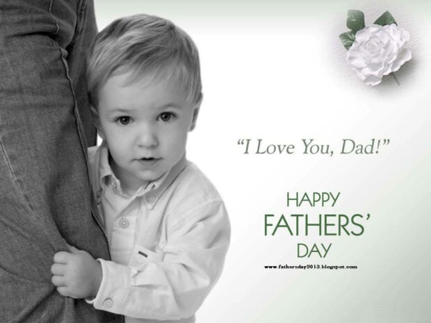 Young boy clings to a man's leg, gazing forward, with 'I Love You, Dad!' and 'Happy Fathers' Day' text alongside a white rose