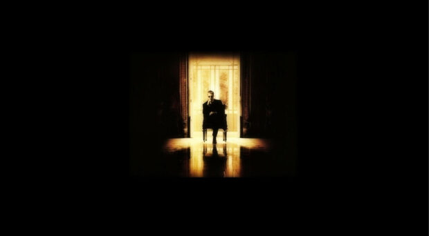 Don Corleone sits framed by a brightly lit doorway, his figure casting a long shadow across the dark room