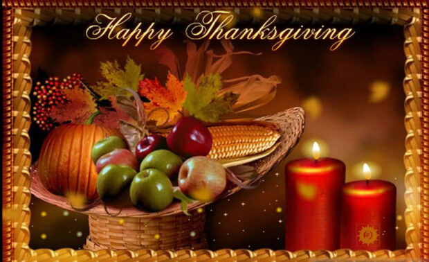 A woven basket brimming with harvest items including corn, apples, a pumpkin, and autumn leaves sits beside two glowing red candles, all enclosed within an ornate golden frame