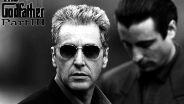 Michael Corleone (Al Pacino) wears sunglasses and stares intently, with Vincent Mancini (Andy Garcia) blurred in the background, featuring the 