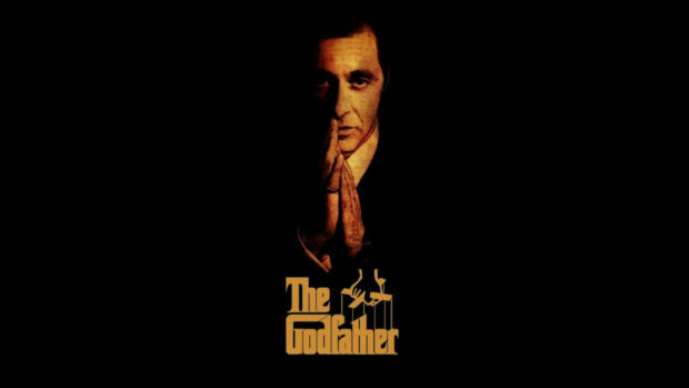 Michael Corleone's face and clasped hands are illuminated in a dramatic orange glow, with the film's title below