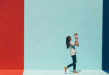 A woman lifts her smiling baby against a vibrant backdrop of colored walls, celebrating their bond