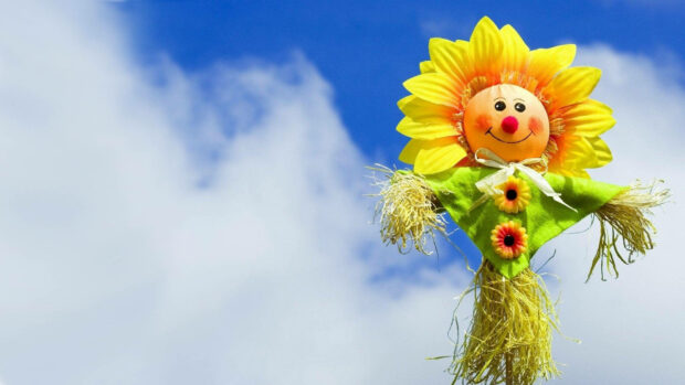 Sunflower scarecrow smiles brightly under a vibrant blue sky with fluffy white clouds