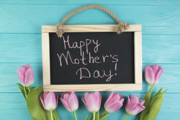 Pink tulips frame a chalkboard displaying 
