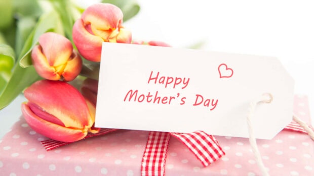 Pink tulips bloom beside a polka-dot gift box, featuring a tag proclaiming a special day
