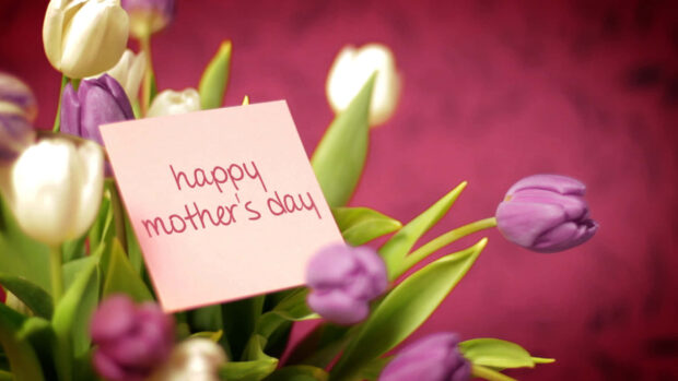 A bouquet of purple and white tulips holds a pink note wishing happiness, set against a soft, blurred background