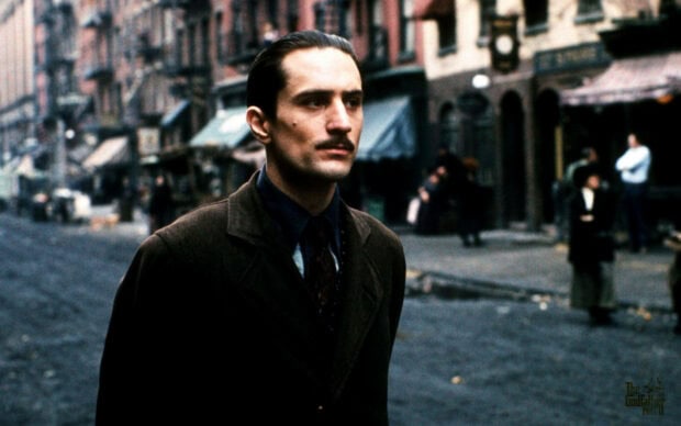 Vito Corleone walks down a gritty New York street, wearing a dark suit and a determined expression