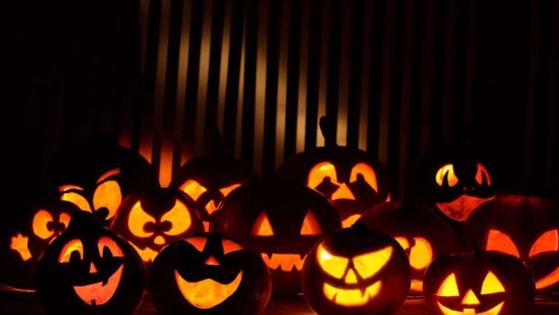 A 3D Halloween Wallpaper featuring a group of glowing jack-o'-lanterns with various spooky faces in a dark setting