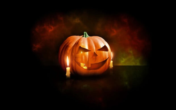 A classic 3D Halloween Wallpaper featuring a carved jack-o'-lantern with two glowing candles