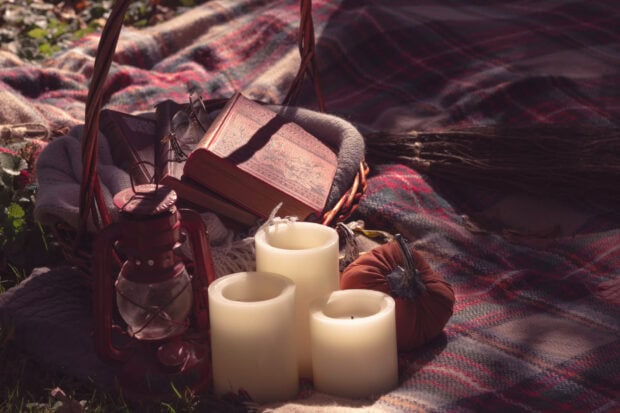 Aesthetic Fall Wallpaper capturing a fall picnic setup with a basket, vintage lantern, candles, and a small pumpkin on a plaid blanket
