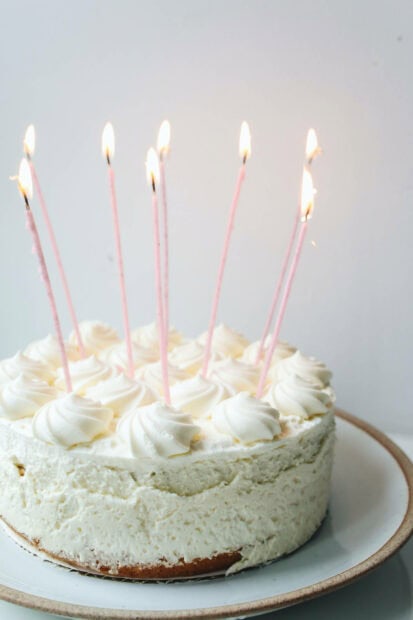 A beautiful Birthday Wallpaper featuring a white frosted cake with numerous lit pink candles