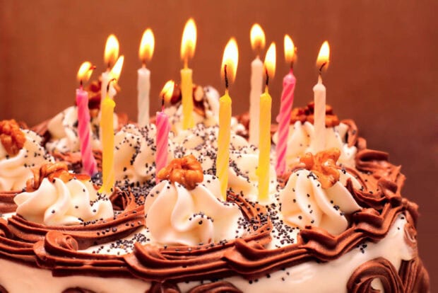 A festive birthday wallpaper featuring a chocolate cake adorned with lit candles and walnuts, perfect for celebrations