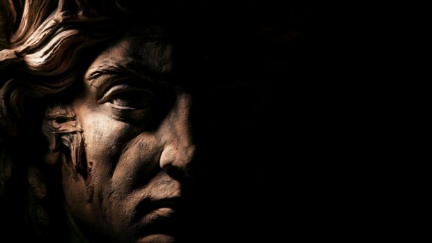 Black aesthetic wallpaper featuring a close-up of a classical statue's face half-covered in deep shadow