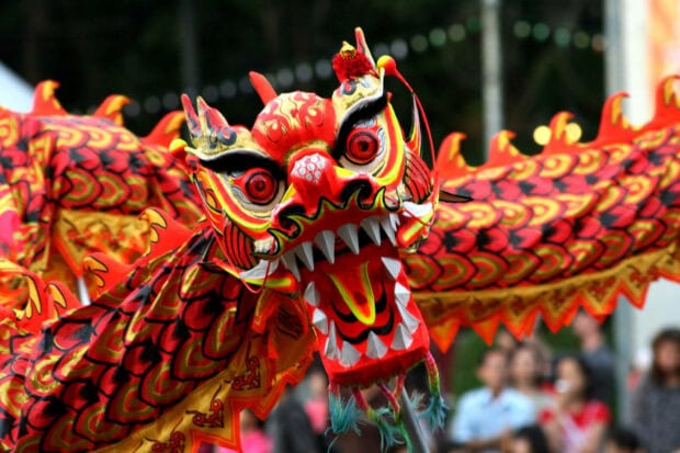 A close-up of a vibrant and colorful Chinese New Year wallpaper featuring a dragon dance head during a festival