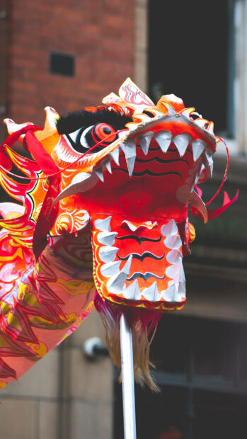 A festive Chinese New Year wallpaper showcasing a close-up of a vibrant red and orange dragon dance head