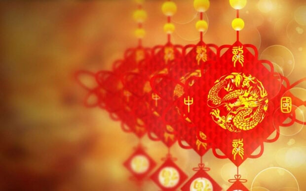 A beautiful Chinese New Year wallpaper showcasing red diamond-shaped ornaments with golden dragon designs against a festive bokeh background