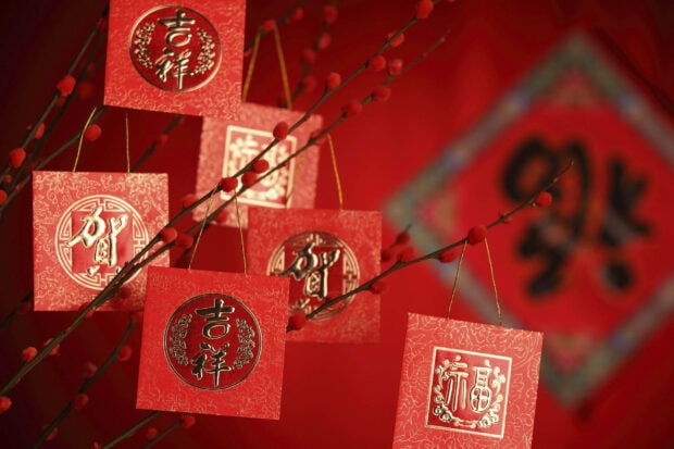 A beautiful Chinese New Year Wallpaper featuring red square ornaments with gold characters hanging from berry branches