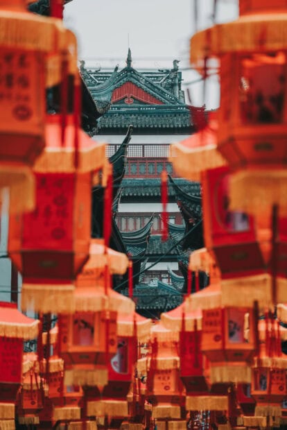 A vibrant Chinese New Year wallpaper featuring traditional red and gold lanterns framing an ancient Chinese building