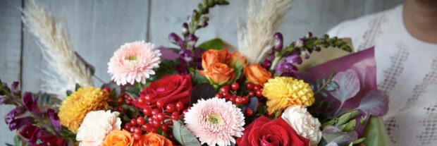 A festive Fall Flowers Wallpaper showcasing a colorful autumn bouquet with roses, gerbera daisies, berries, and pampas grass