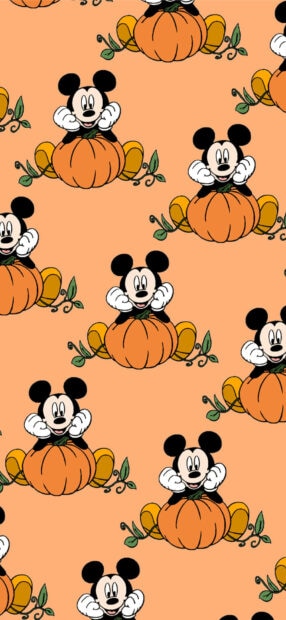 Cute Halloween Wallpaper with a repeating pattern of Mickey Mouse sitting on pumpkins on an orange background