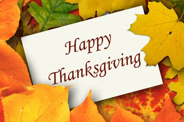 A cute Thanksgiving wallpaper showing a white card with "Happy Thanksgiving" text surrounded by colorful autumn leaves