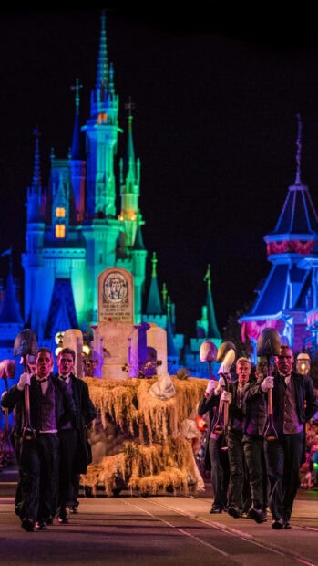A captivating Disney Halloween wallpaper featuring a night parade with performers holding shovels in front of Cinderella Castle, illuminated with blue and green lights
