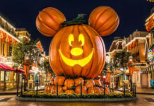 A stunning Disney Halloween wallpaper showing a giant Mickey Mouse pumpkin at night on a festive park street