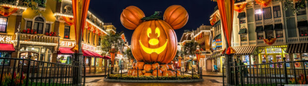 A stunning Disney Halloween wallpaper showing a giant Mickey Mouse pumpkin at night on a festive park street