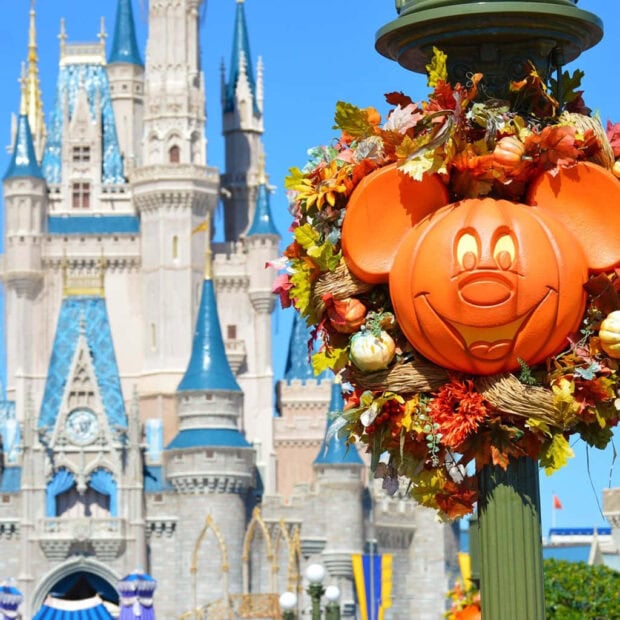 Disney Halloween wallpaper showcasing a Mickey Mouse pumpkin wreath on a lamppost with a Disney castle in the background