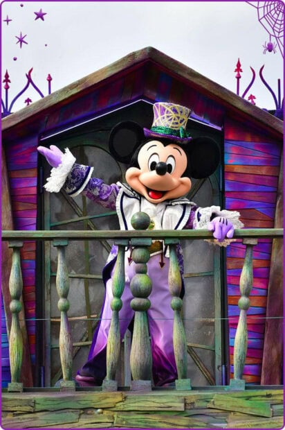 A captivating Disney Halloween Wallpaper showing Mickey Mouse in a vibrant purple and gold costume on a decorative balcony