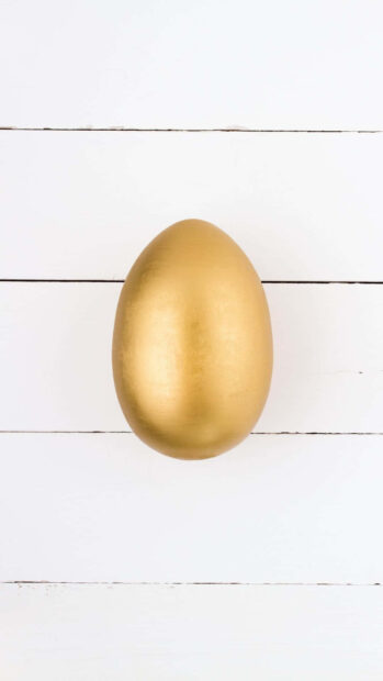 Easter Egg Wallpaper featuring a luxurious golden egg centered on a clean white wooden background