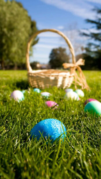 A scenic Easter egg wallpaper showing colorful eggs hidden in green grass with a blurred basket