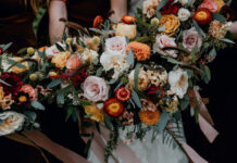 A beautiful Fall Flowers Wallpaper featuring an elegant autumn bouquet with pink, orange, and red roses, dahlias, and eucalyptus leaves