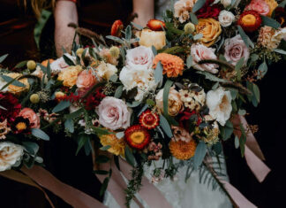 A beautiful Fall Flowers Wallpaper featuring an elegant autumn bouquet with pink, orange, and red roses, dahlias, and eucalyptus leaves